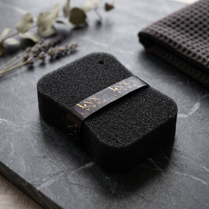 LYVAX Smart Bath Sponge close-up showing porous texture and branded ribbon on dark marble
